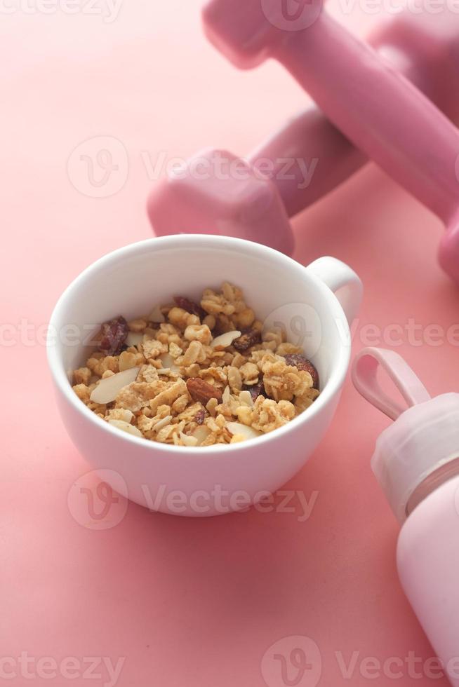 petit-déjeuner aux céréales et haltère dans un bol sur fond rose photo