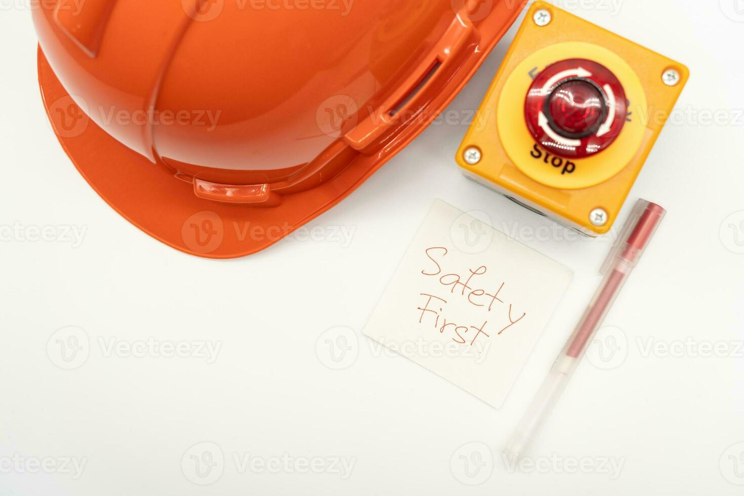 Orange sécurité chapeau avec message sécurité d'abord, rouge stylo et urgence Arrêtez bouton isolé sur blanc Contexte. sécurité premier concept. copie espace pour texte. photo