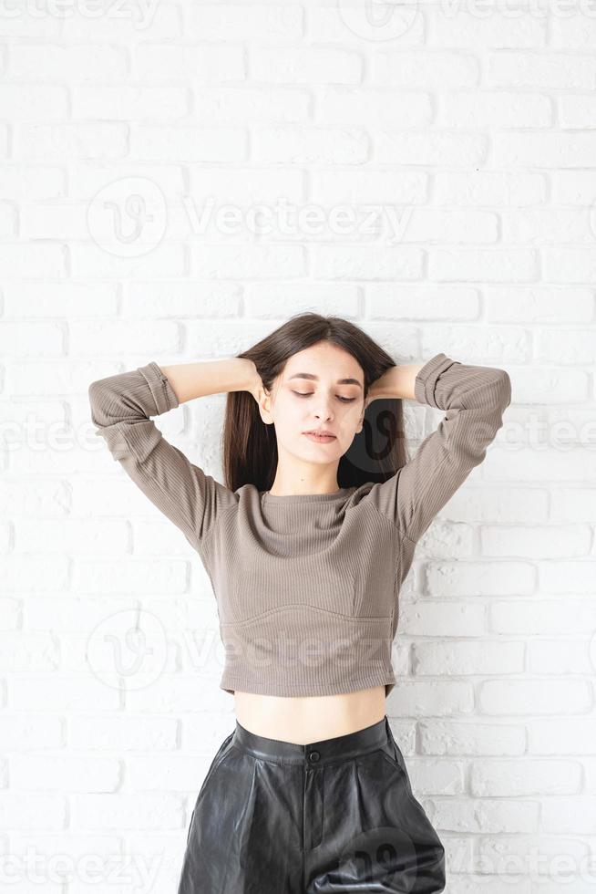 femme aux cheveux longs sur fond de mur de briques blanches photo