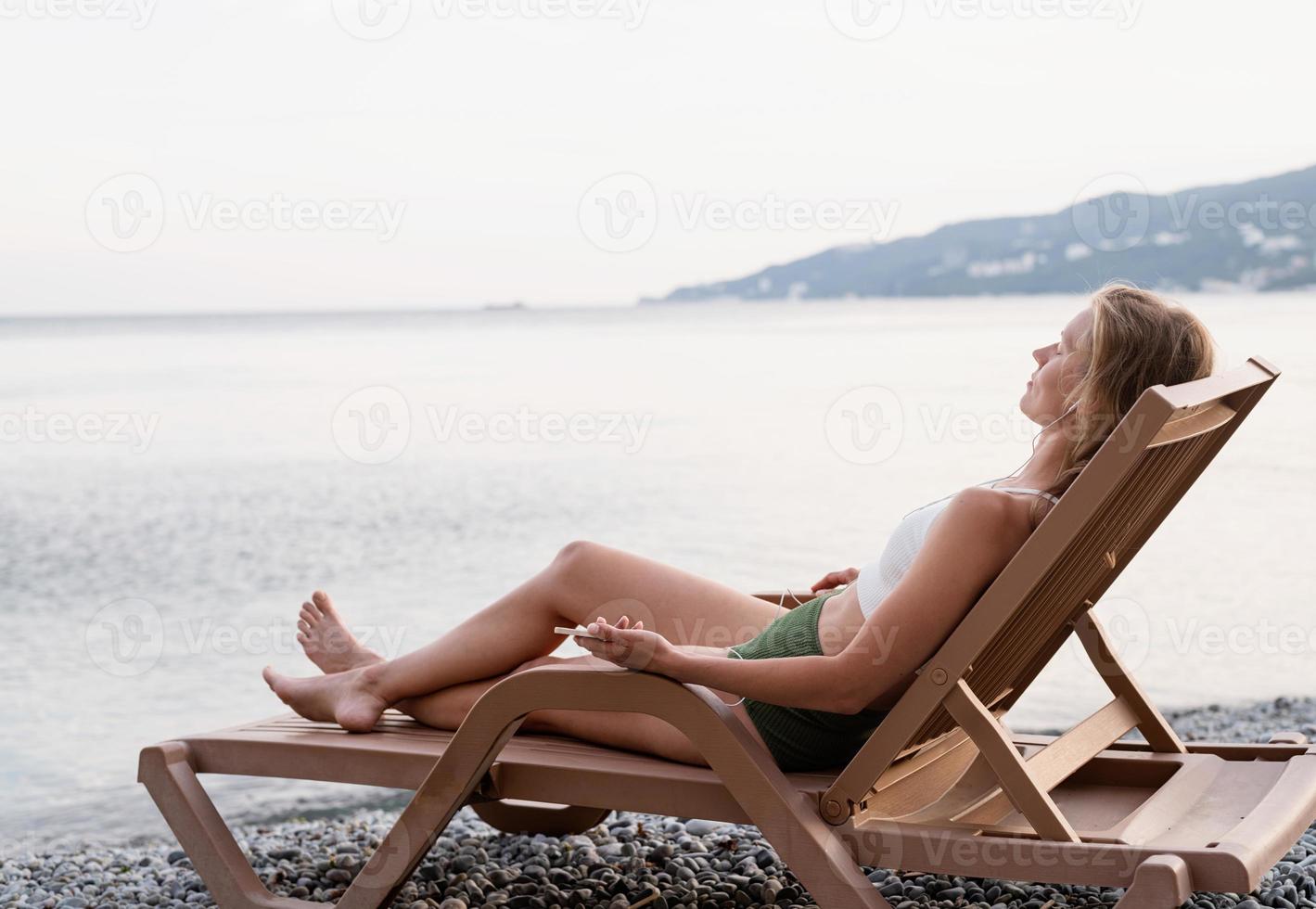 femme allongée sur la chaise longue écoutant de la musique photo