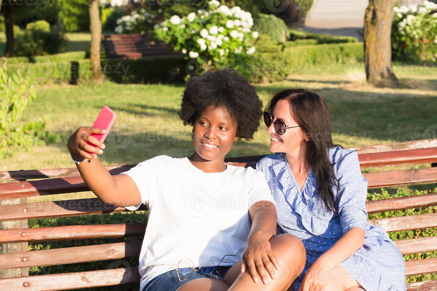 des filles heureuses de différentes nationalités prennent des selfies en été photo