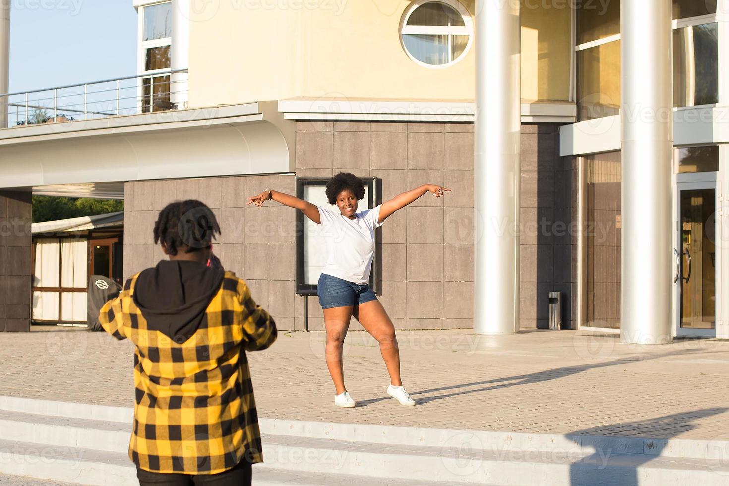 une fille prend des photos d'un ami dans la rue en été