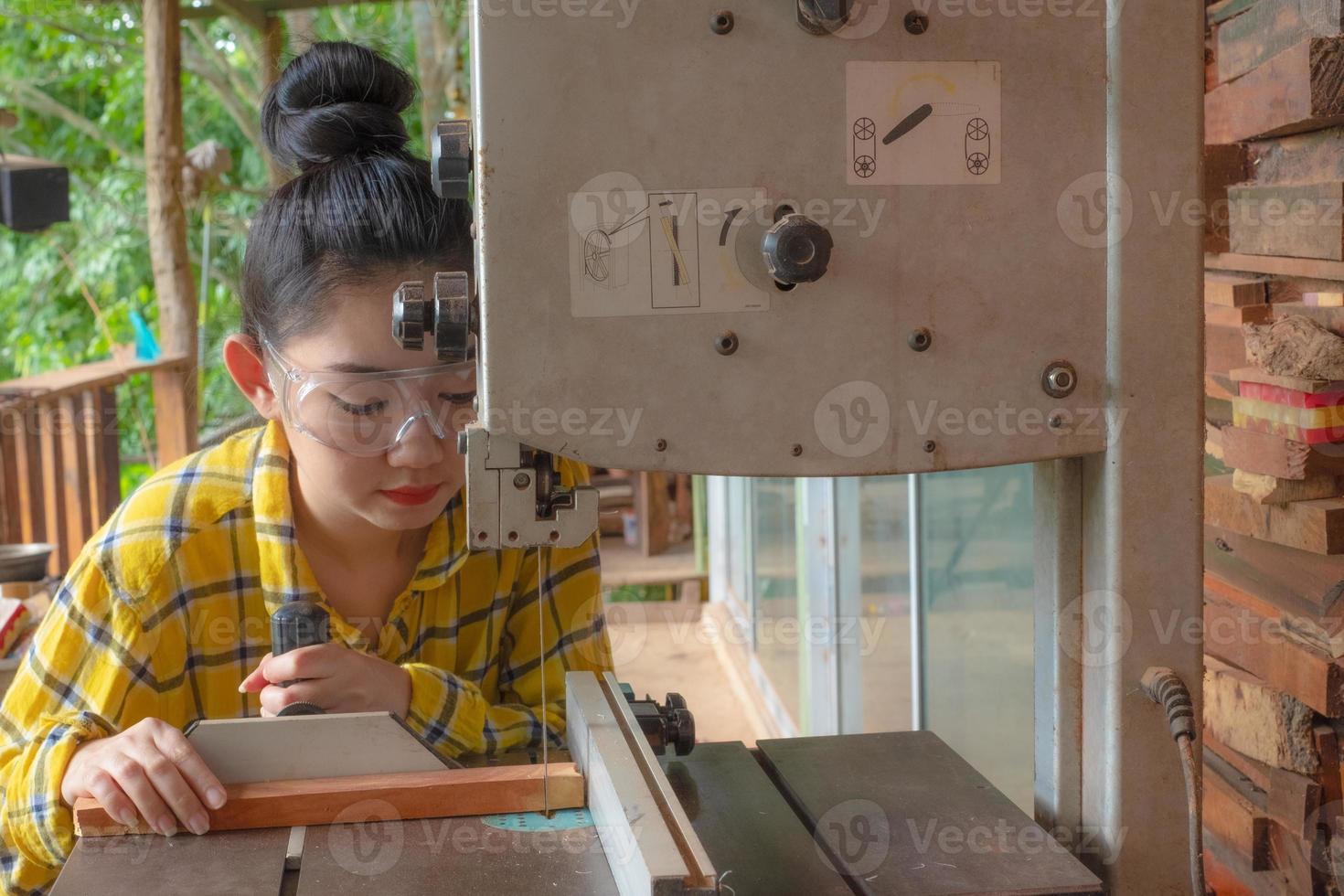 Les femmes debout sont du travail artisanal du bois coupé sur un banc de travail photo