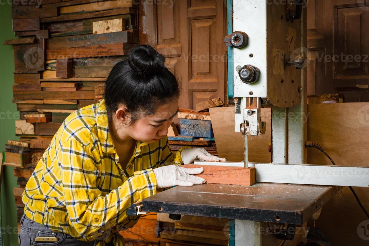 Les femmes debout sont du travail artisanal du bois coupé sur un banc de travail photo