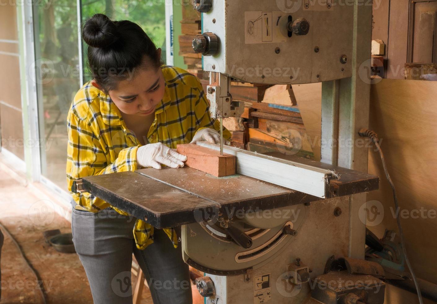 Les femmes debout sont du travail artisanal du bois coupé sur un banc de travail photo