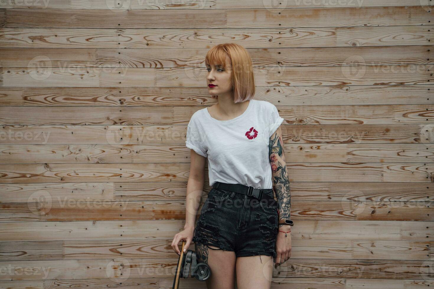 Jeune femme permanent à en bois mur avec planche à roulette photo