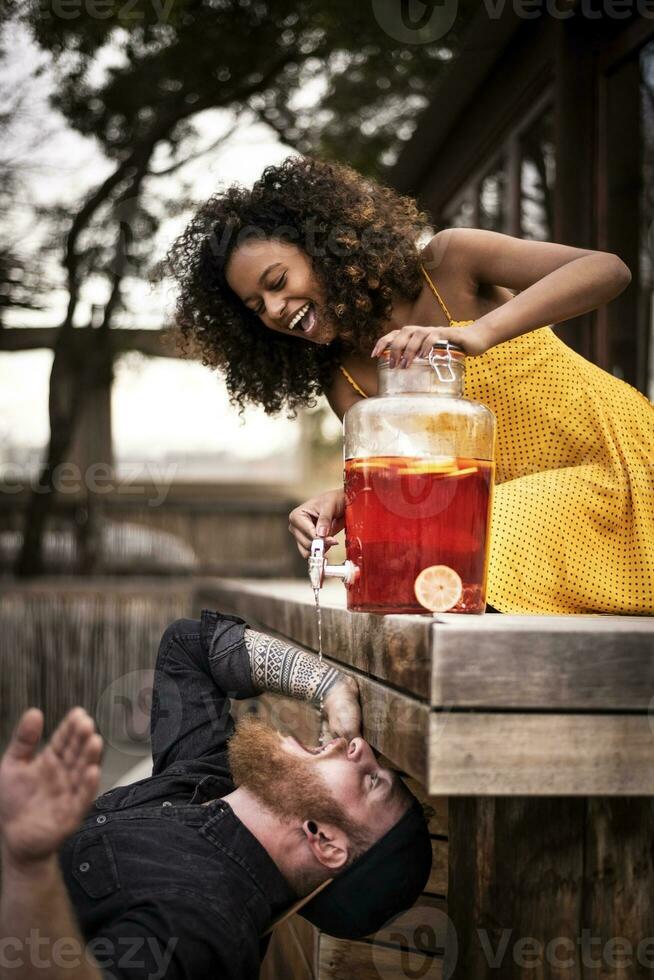 content femme verser la glace thé dans petit ami bouche photo