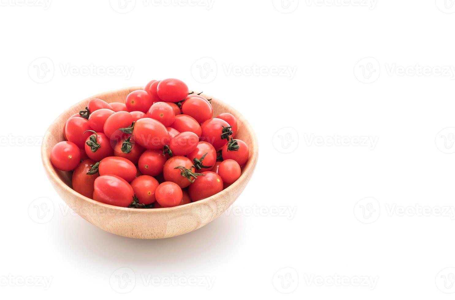 Tomates fraîches dans un bol en bois sur fond blanc photo