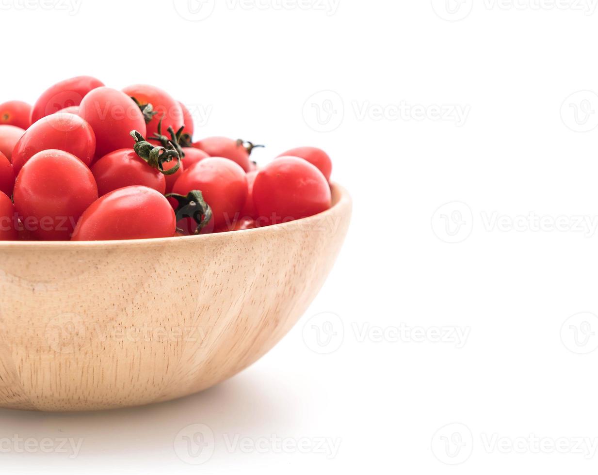 Tomates fraîches dans un bol en bois sur fond blanc photo