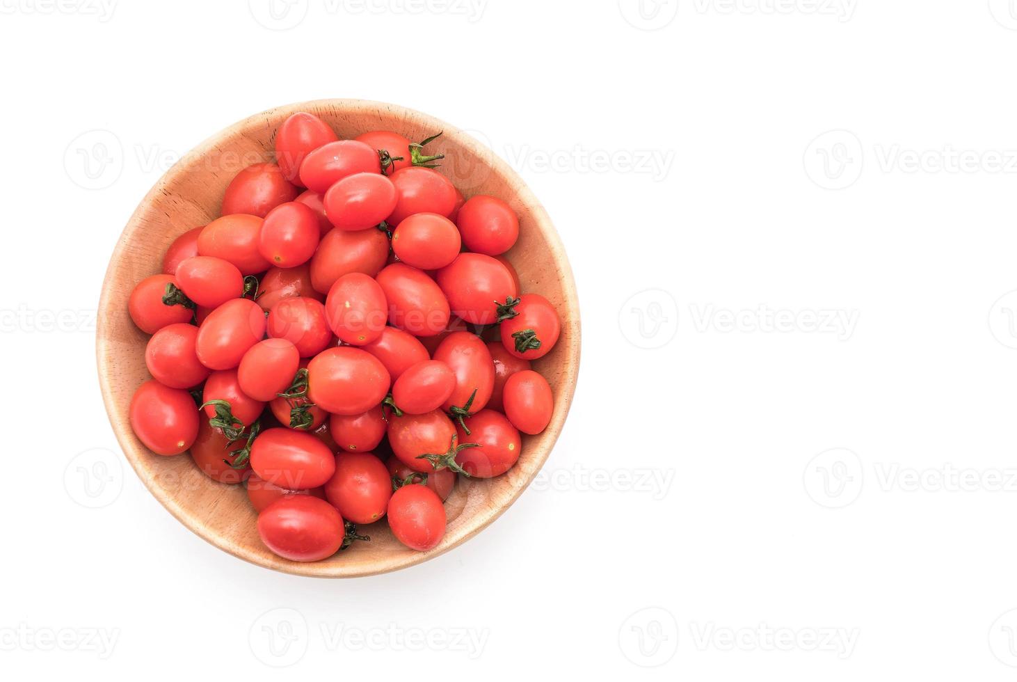 Tomates fraîches dans un bol en bois sur fond blanc photo