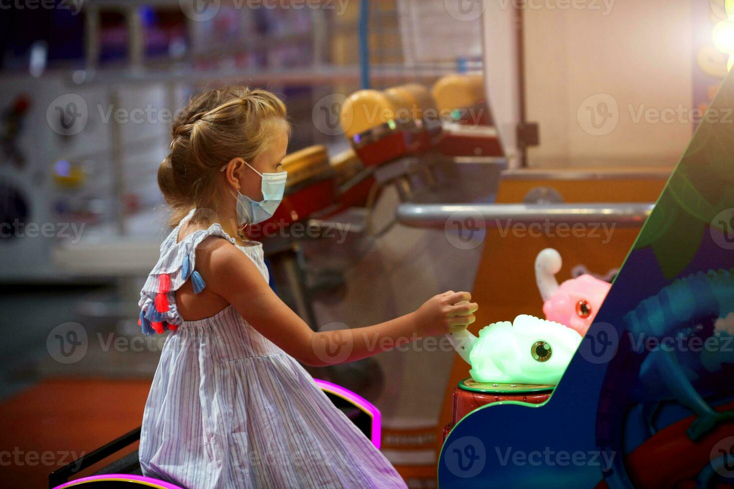 une peu fille dans une médical masque pièces une Jeu machine dans le enfants chambre. photo