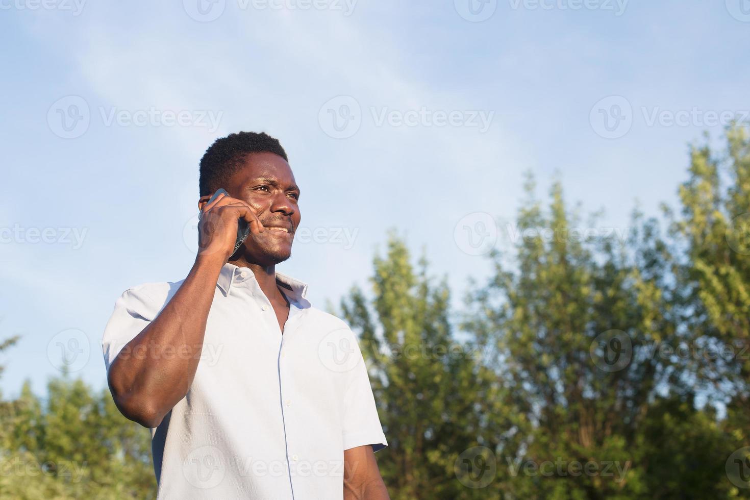 heureux afro-américain avec un téléphone dans la rue photo