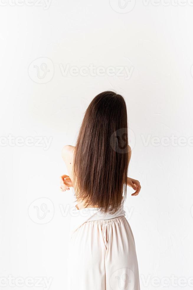 femme dans des vêtements confortables blancs sur fond blanc, vue de derrière photo