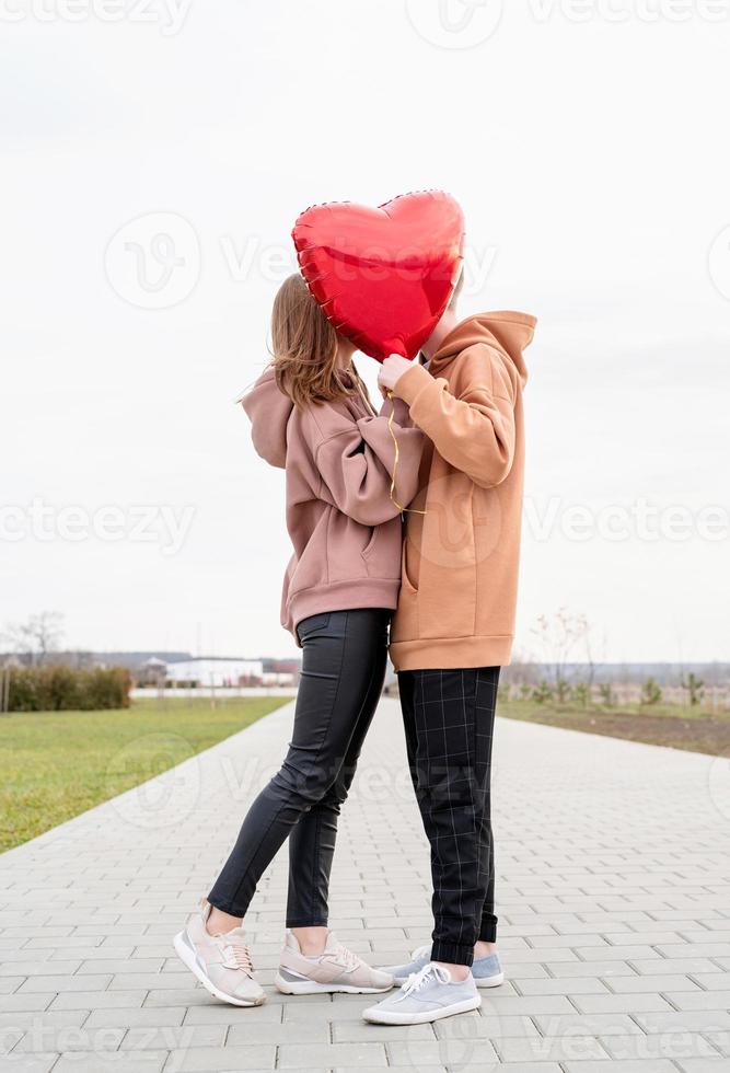 couple avec des ballons rouges embrassant et s'embrassant à l'extérieur s'amusant photo