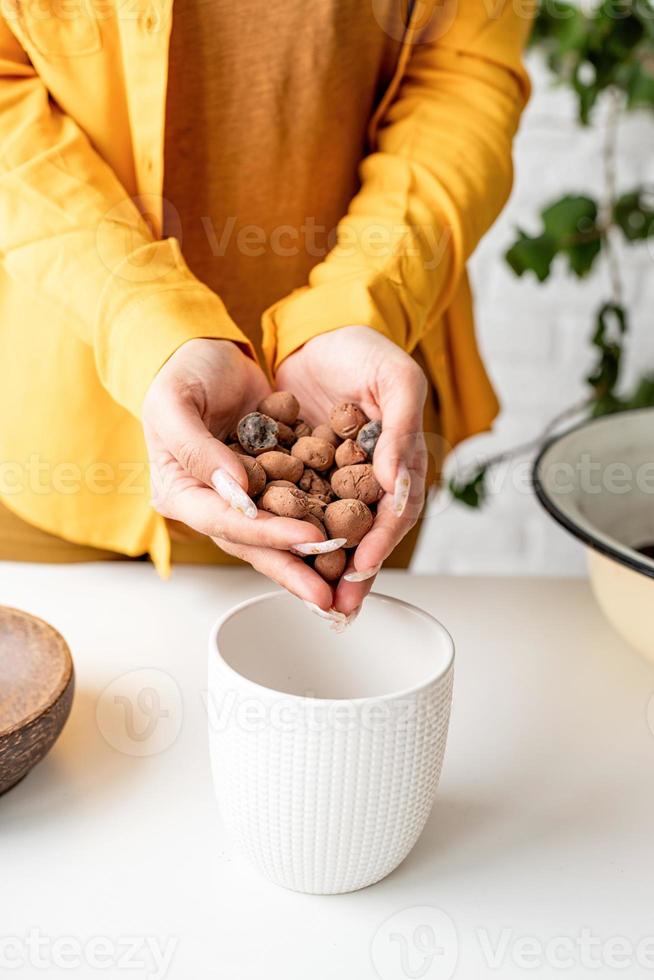 Mains de jardinier femme mettant le drainage et le sol dans un nouveau pot de fleurs photo