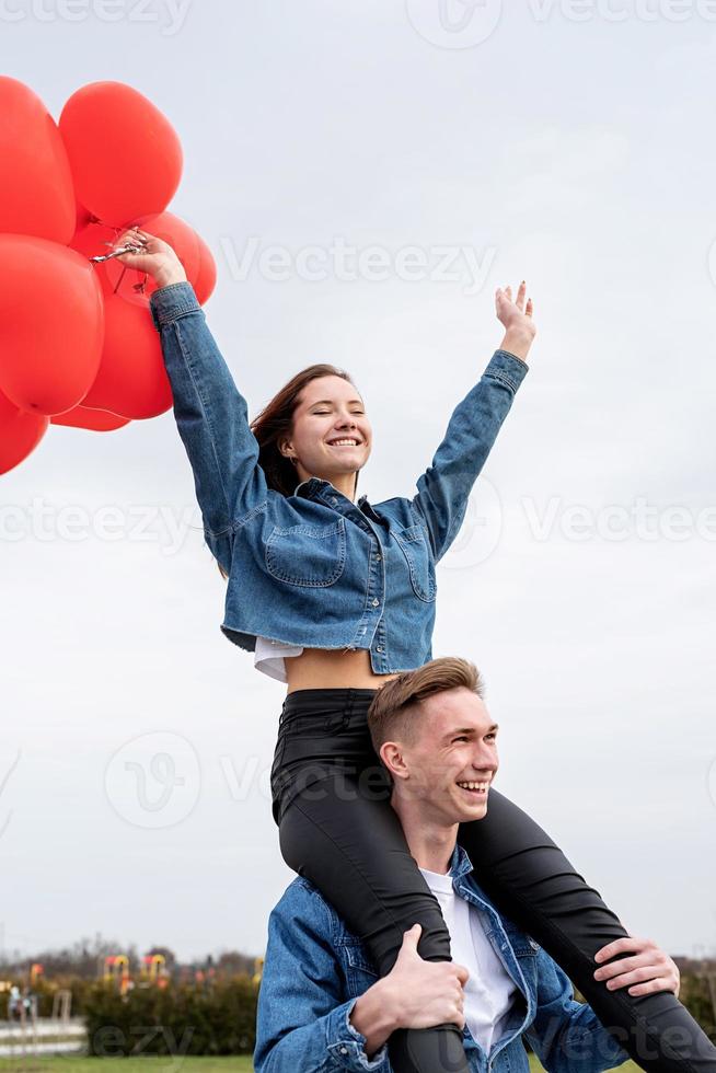 jeune couple d'amoureux avec des ballons rouges embrassant à l'extérieur s'amusant photo