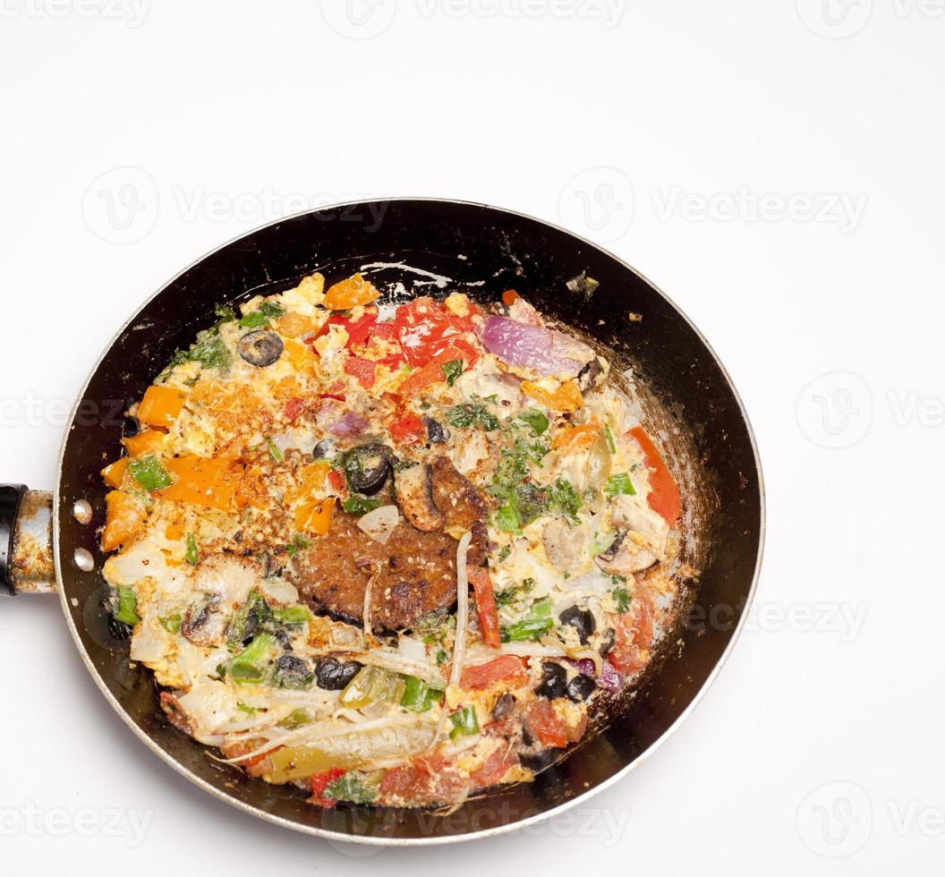 omelette aux légumes dans une poêle en fer noir sur fond blanc photo