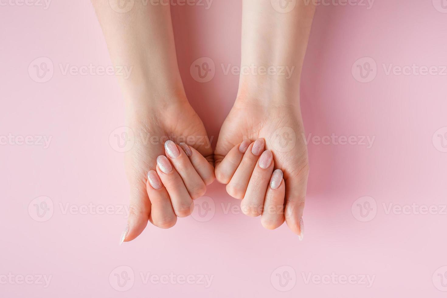 concept de soins de la peau. belles mains féminines sur fond rose photo