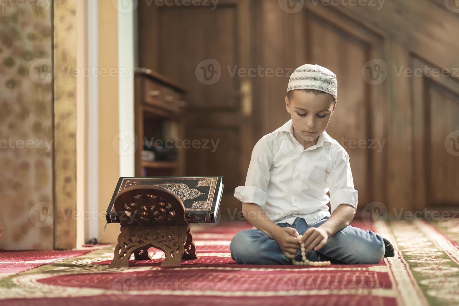 ramadan kareem, beau garçon musulman prie dans la mosquée photo