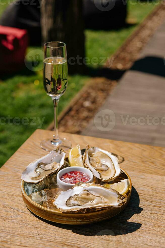 ouvert Huîtres et citron avec blanc du vin sur le table photo