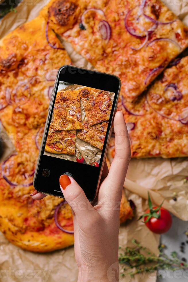 femelle main fabrication une photo de Pizza avec une mobile téléphone