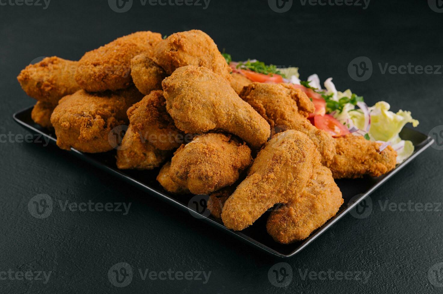 Profond frit poulet sur noir assiette photo