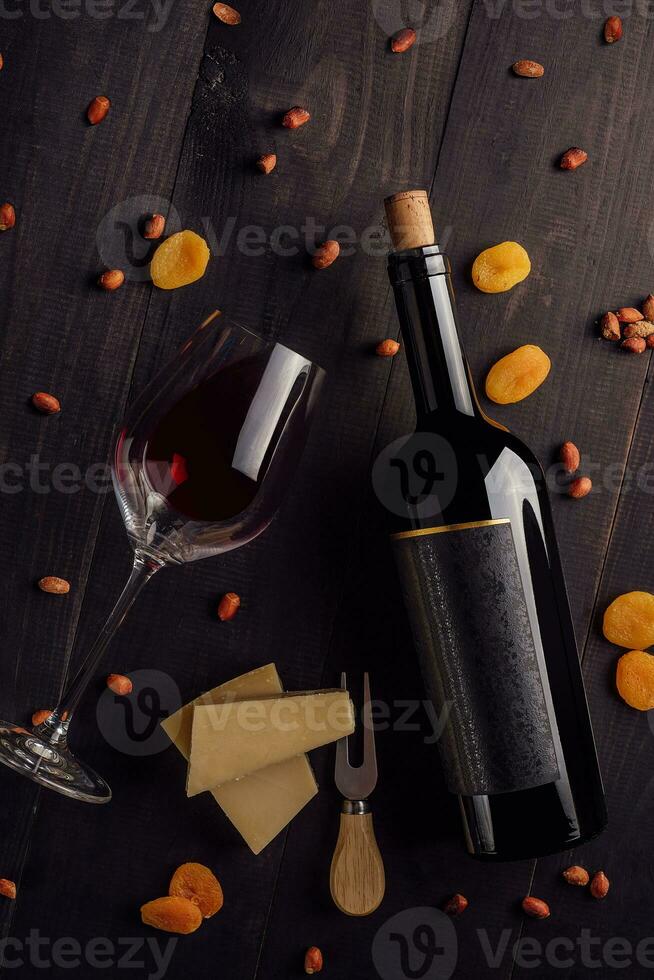 verre et bouteille de rouge du vin avec fromage, séché abricots et des noisettes photo