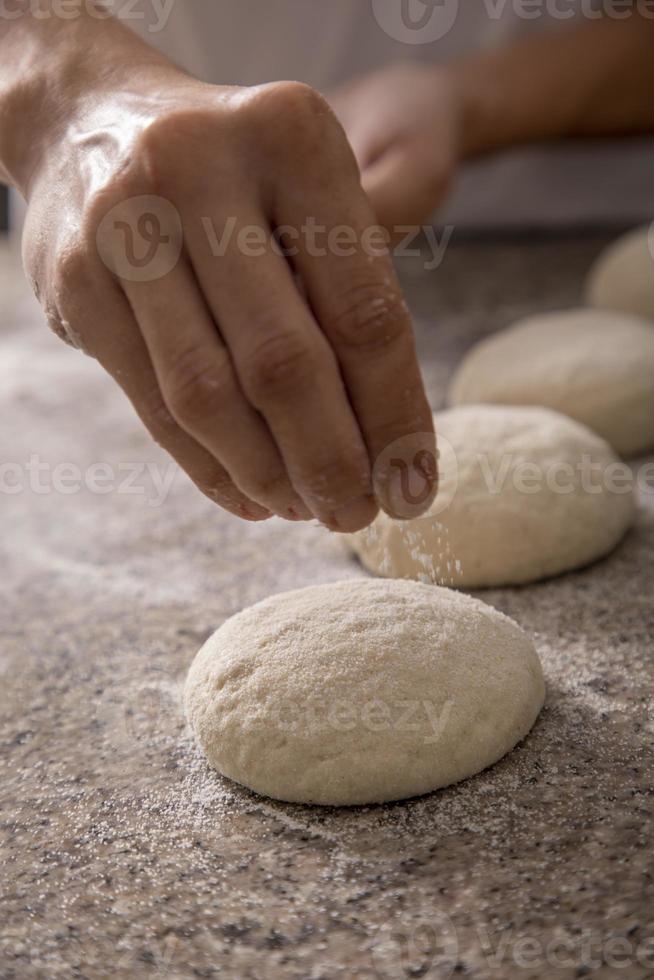 femme mains saupoudrer la farine de pizza close-up photo