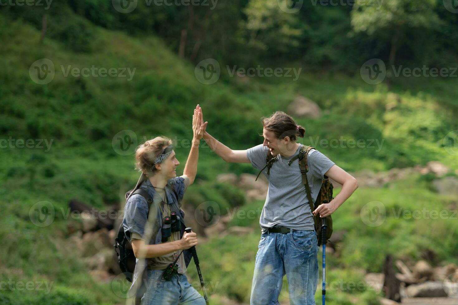 deux homme randonnée dans le forêt avec sacs à dos et trekking poteaux photo