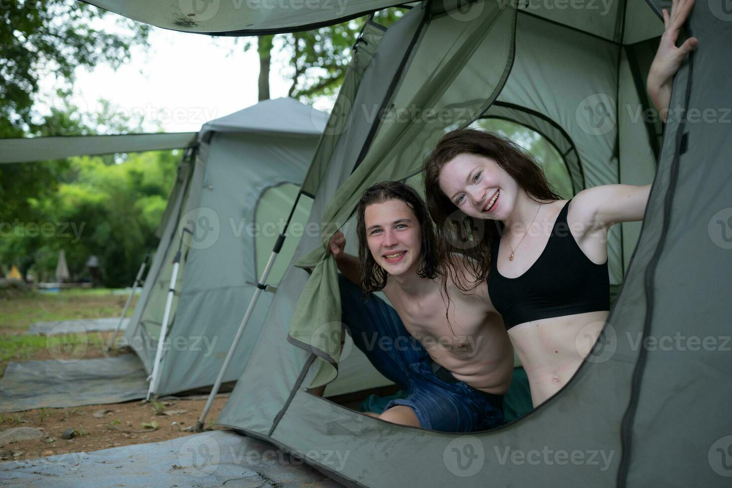 Jeune couple camping dans tente dans forêt souriant content et détendu à la recherche à caméra photo