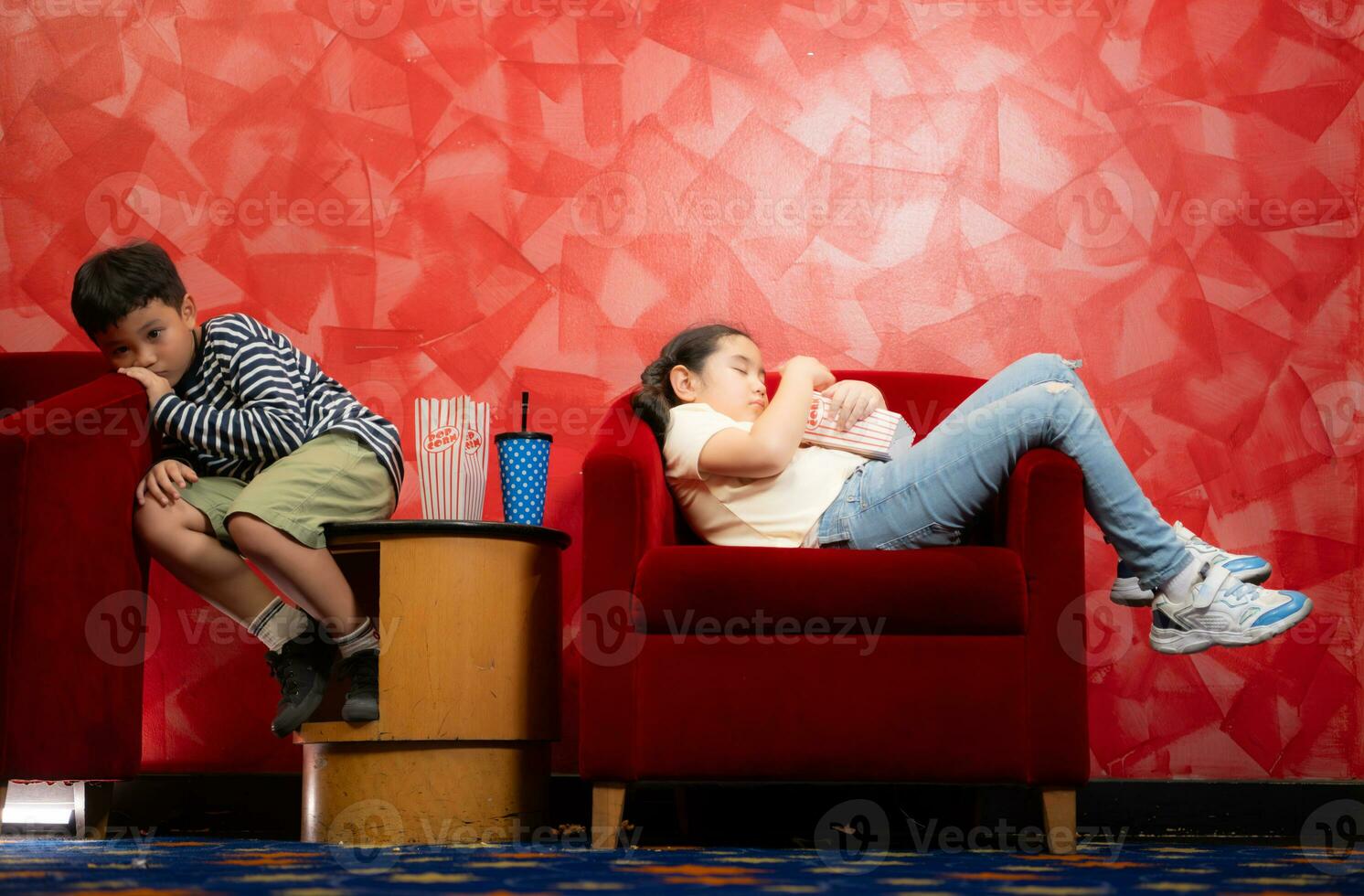 garçon et fille du repos et attendre pour en train de regarder une film sur le rouge canapé dans le de face de cinéma photo