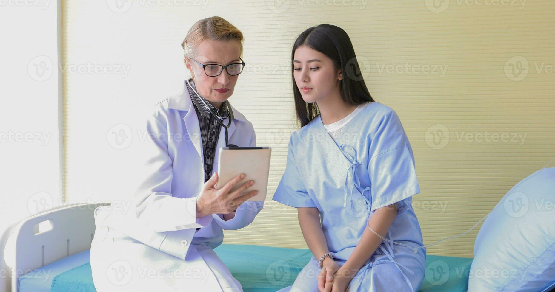 asiatique femme patient séance avec médecin à propos sa maladies et montrant radiographie résultats avec du sang pression et cœur taux la mesure avec stéthoscope photo
