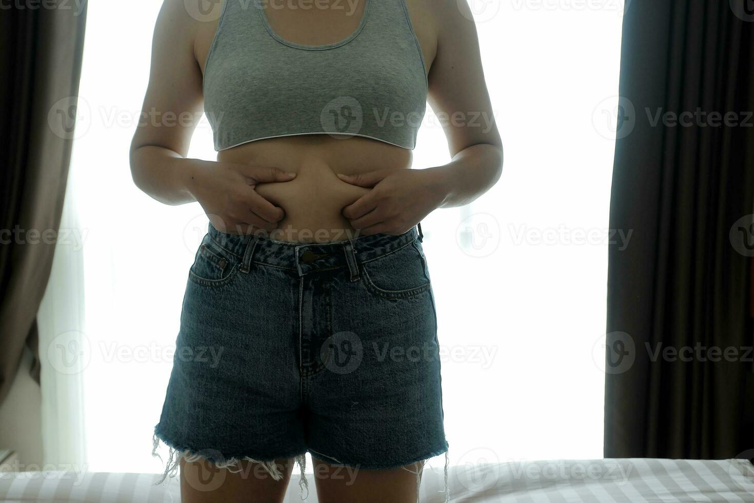 proche en haut de une ventre avec cicatrice de césarienne et abdominal graisse. aux femmes santé. une femme habillé en haut dans tenue de sport démontrant sa imparfait corps après une accouchement avec garderie sur le Contexte. photo