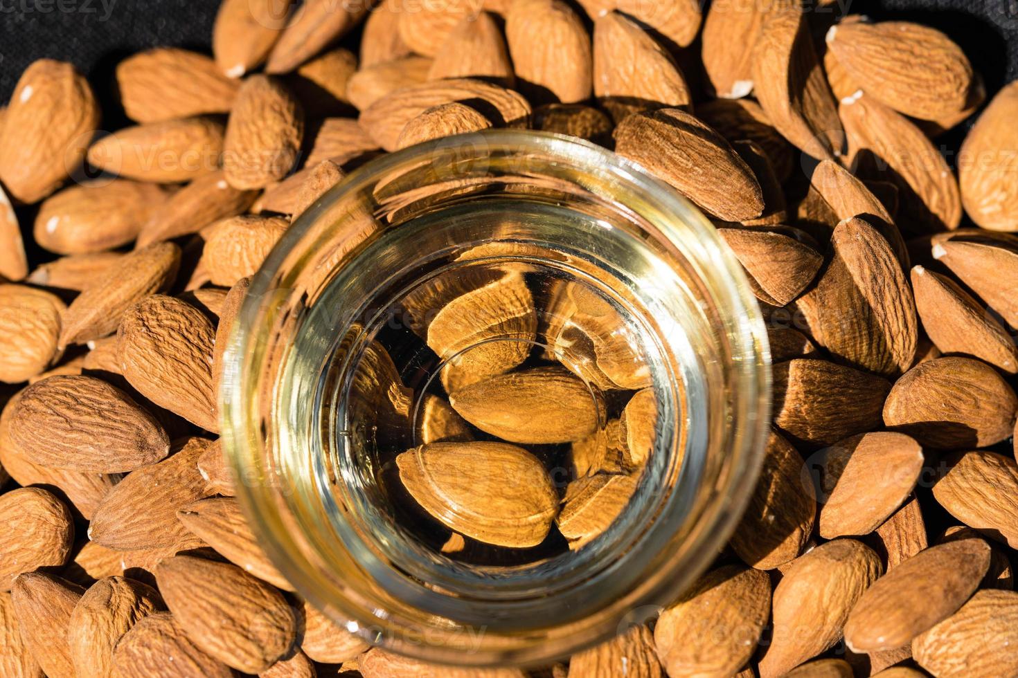 un tas d'amandes et un verre à l'huile d'amande photo