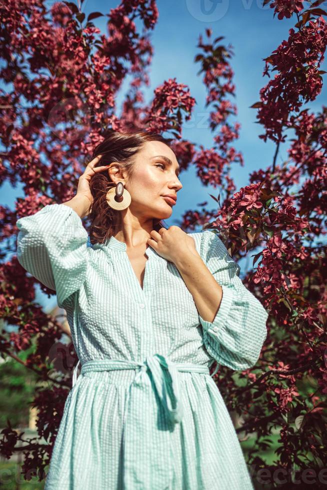 une jeune fille se tient dans le parc sous un pommier en fleurs photo