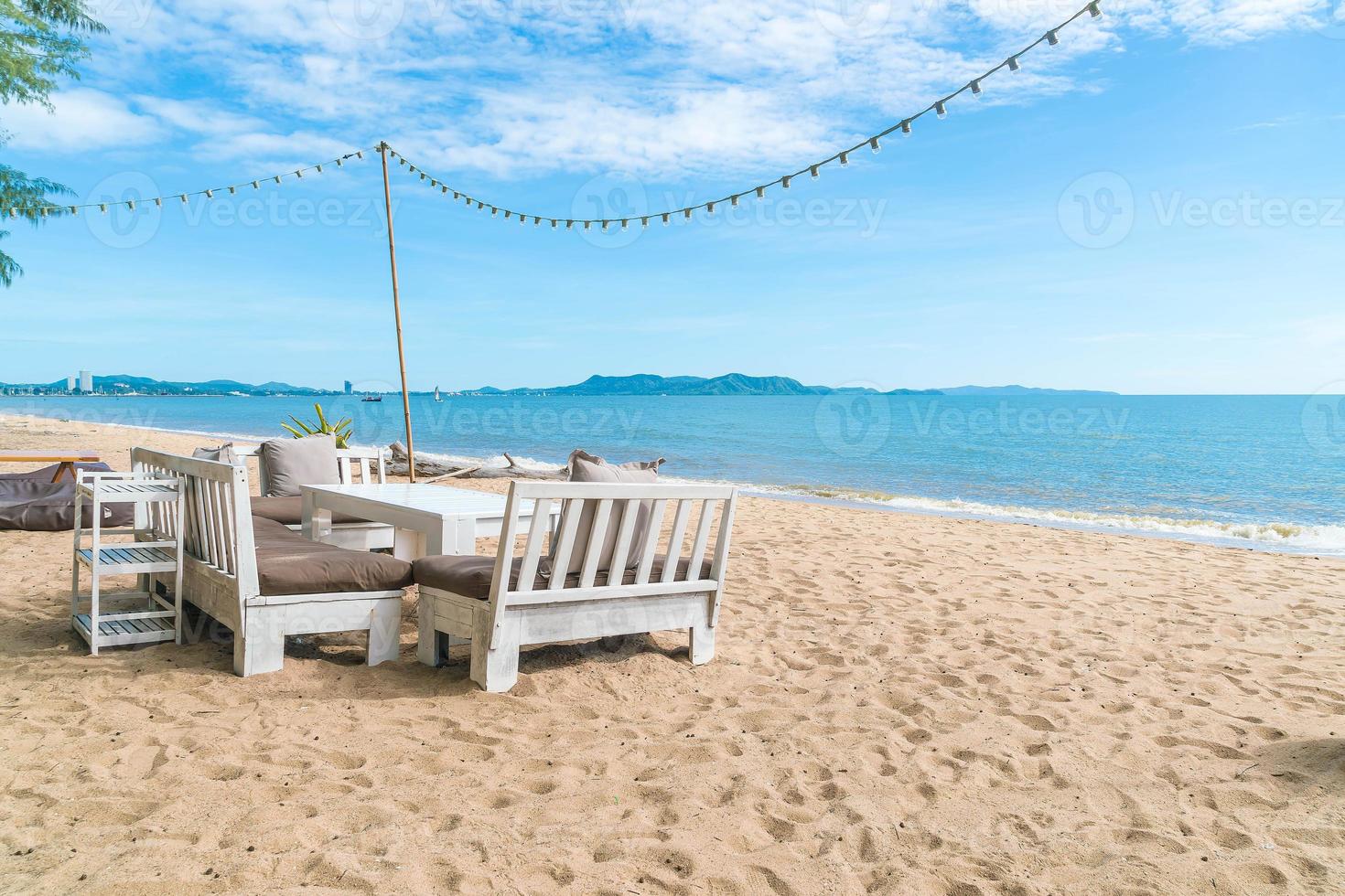 chaises blanches et table sur la plage avec vue sur l'océan bleu et le ciel clair photo