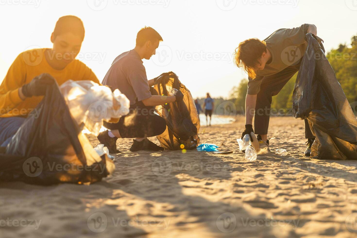 Terre journée. bénévoles militants équipe recueille des ordures nettoyage de plage côtier zone. groupe de gens met Plastique poubelle dans des ordures Sacs sur océan rive. environnement conservation. photo