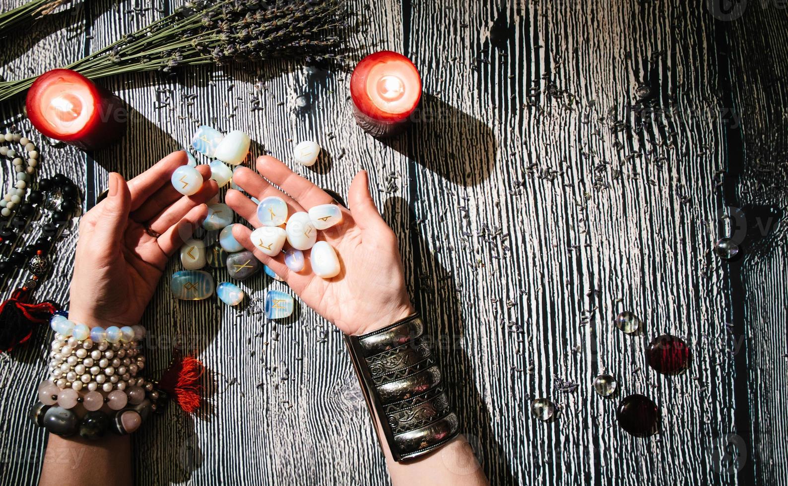 mains de diseuse de bonne aventure avec runes en pierre, intérieur mystique. photo