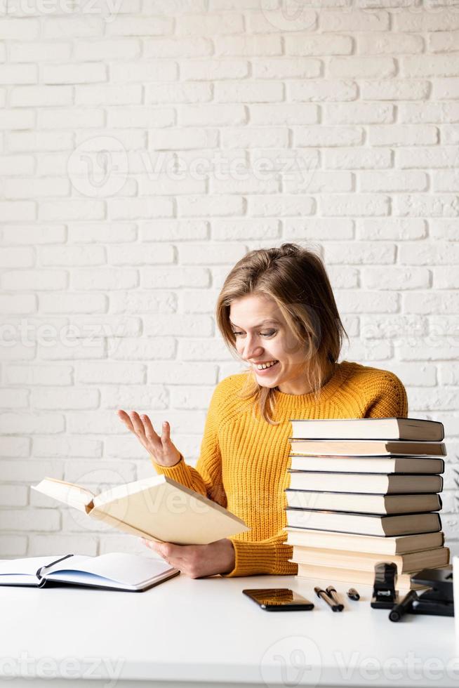 jeune femme souriante en pull jaune lisant un livre et riant photo