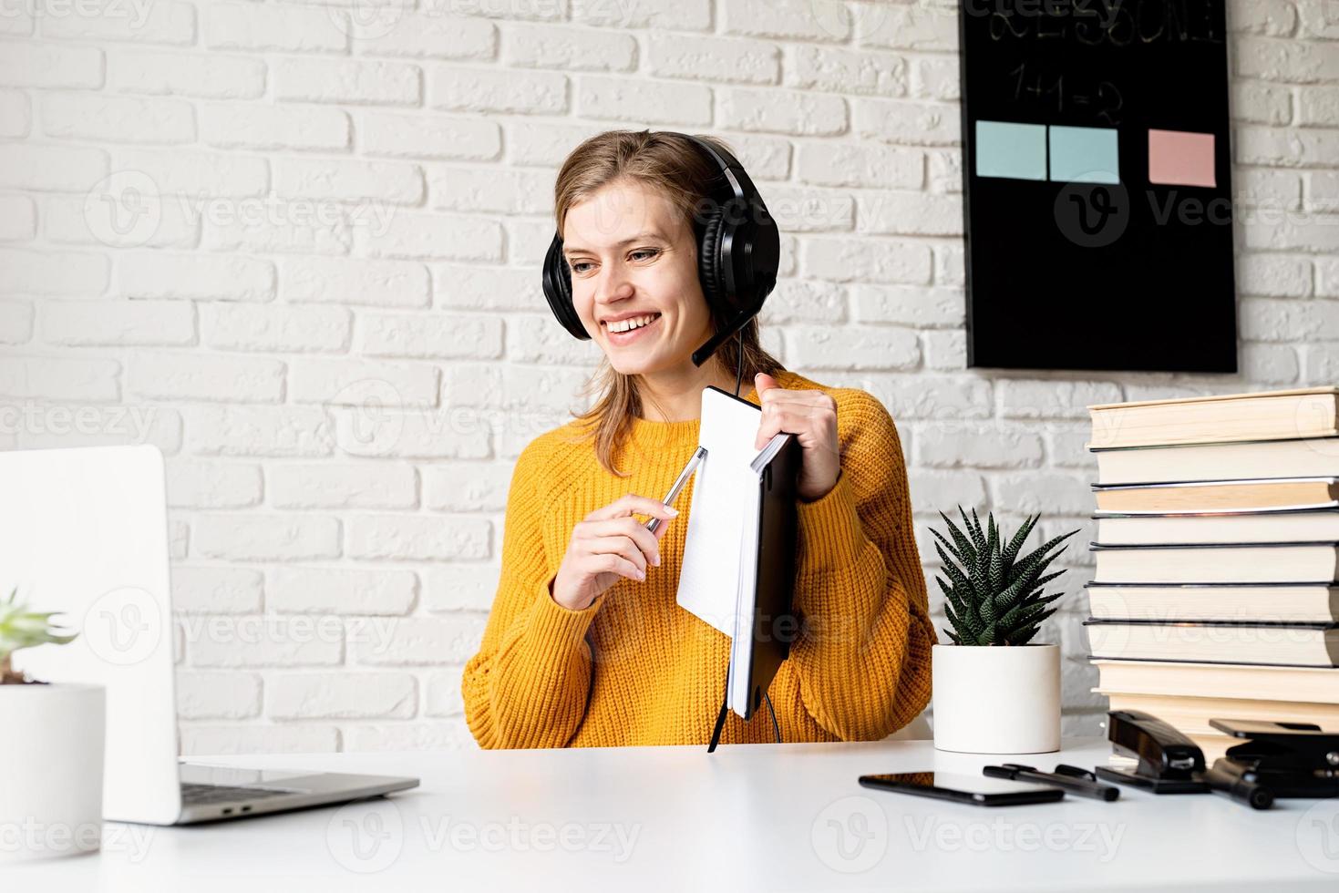 femme au casque étudiant en ligne à l'aide d'un ordinateur portable écrivant dans un ordinateur portable photo