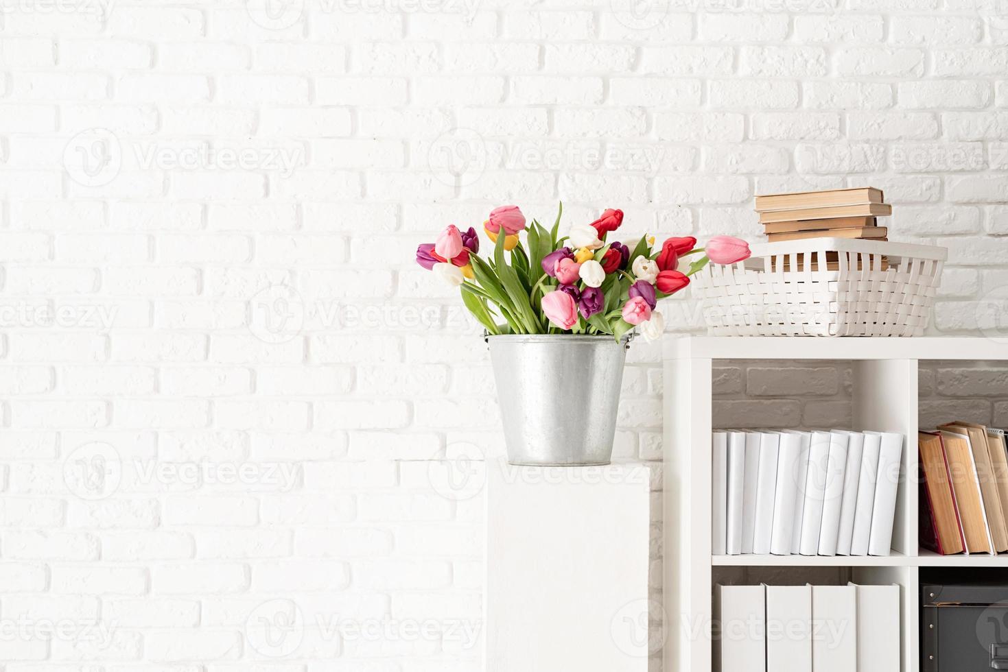 seau de fleurs de tulipes à côté de la bibliothèque photo