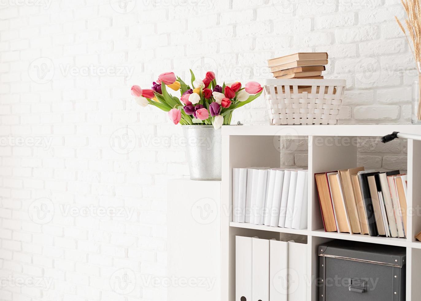 seau de fleurs de tulipes à côté de la bibliothèque photo