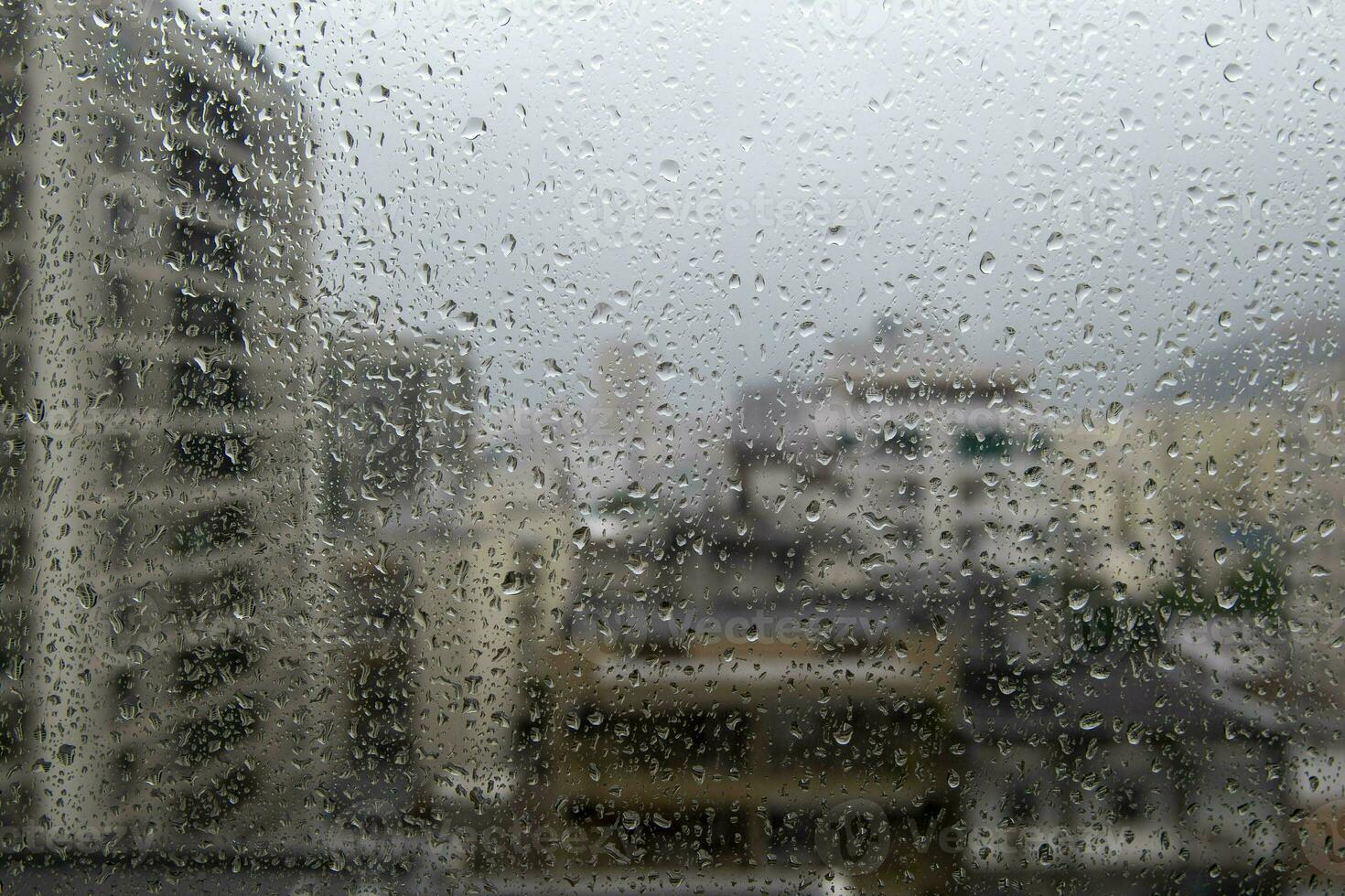 fenêtre verre avec gouttes de pluie montrant flou ville dans le Contexte photo