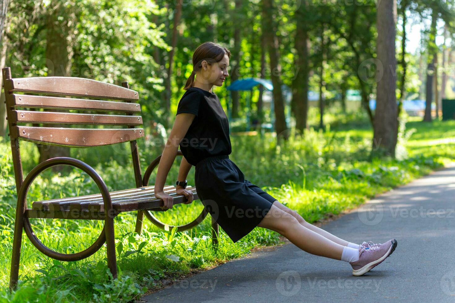 magnifique Jeune sportif femme dans noir T-shirt, noir short et rose formateurs chauffage en haut exercice triceps photo