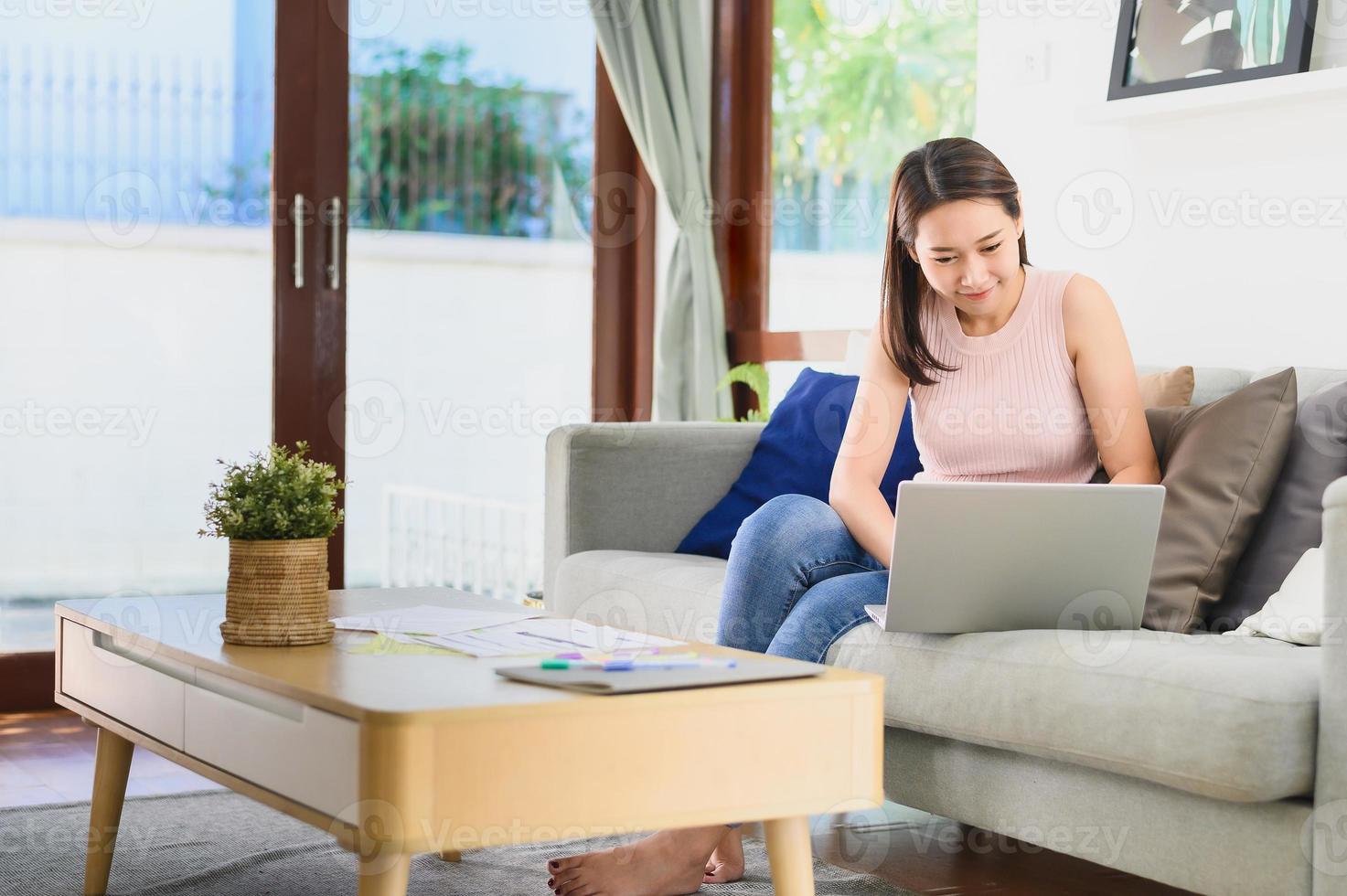 femme asiatique utilisant un ordinateur portable travaillant à la maison photo