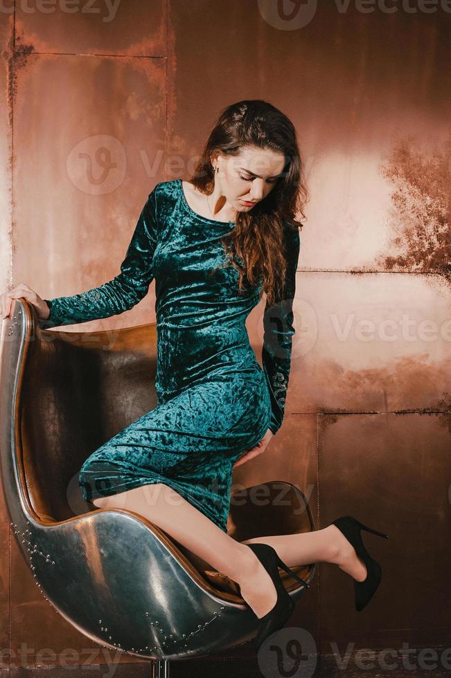 jolie jeune femme vêtue d'une robe bleu velours, sur une chaise photo