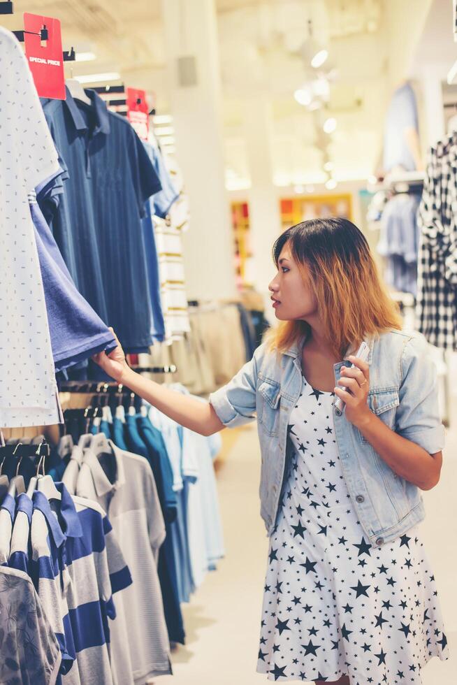 heureuse jeune femme regardant la vente de vêtements dans la boutique. photo
