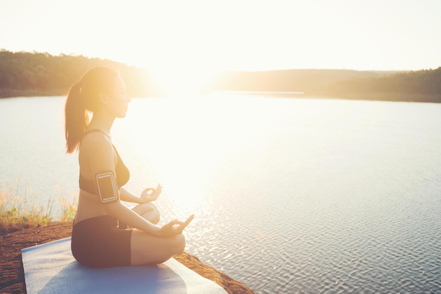 jeune femme en bonne santé pratique le yoga au lac de montagne pendant le coucher du soleil. photo