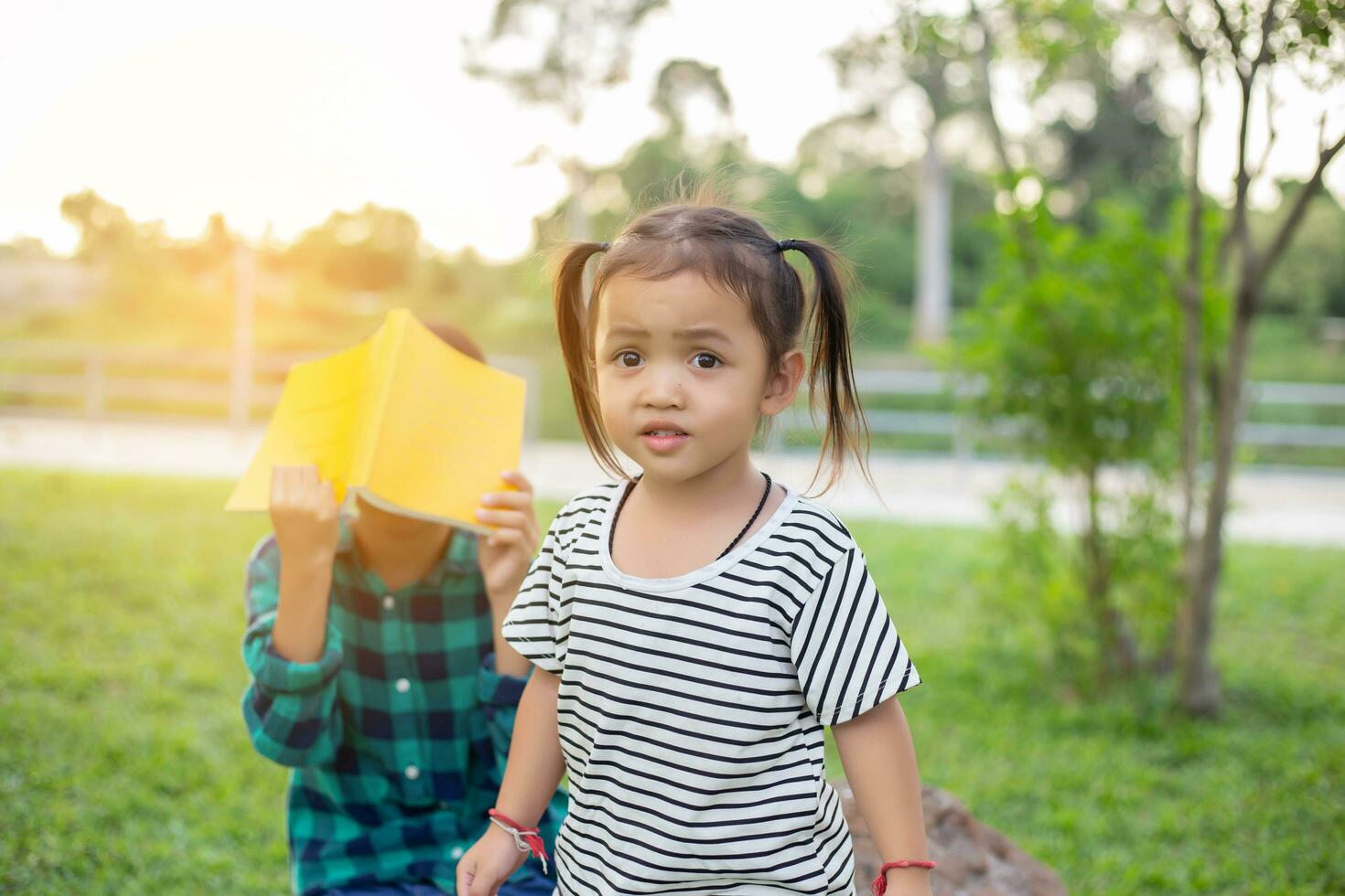 mignonne peu fille en train de lire livre sur arbre dans parc.sstkhome photo