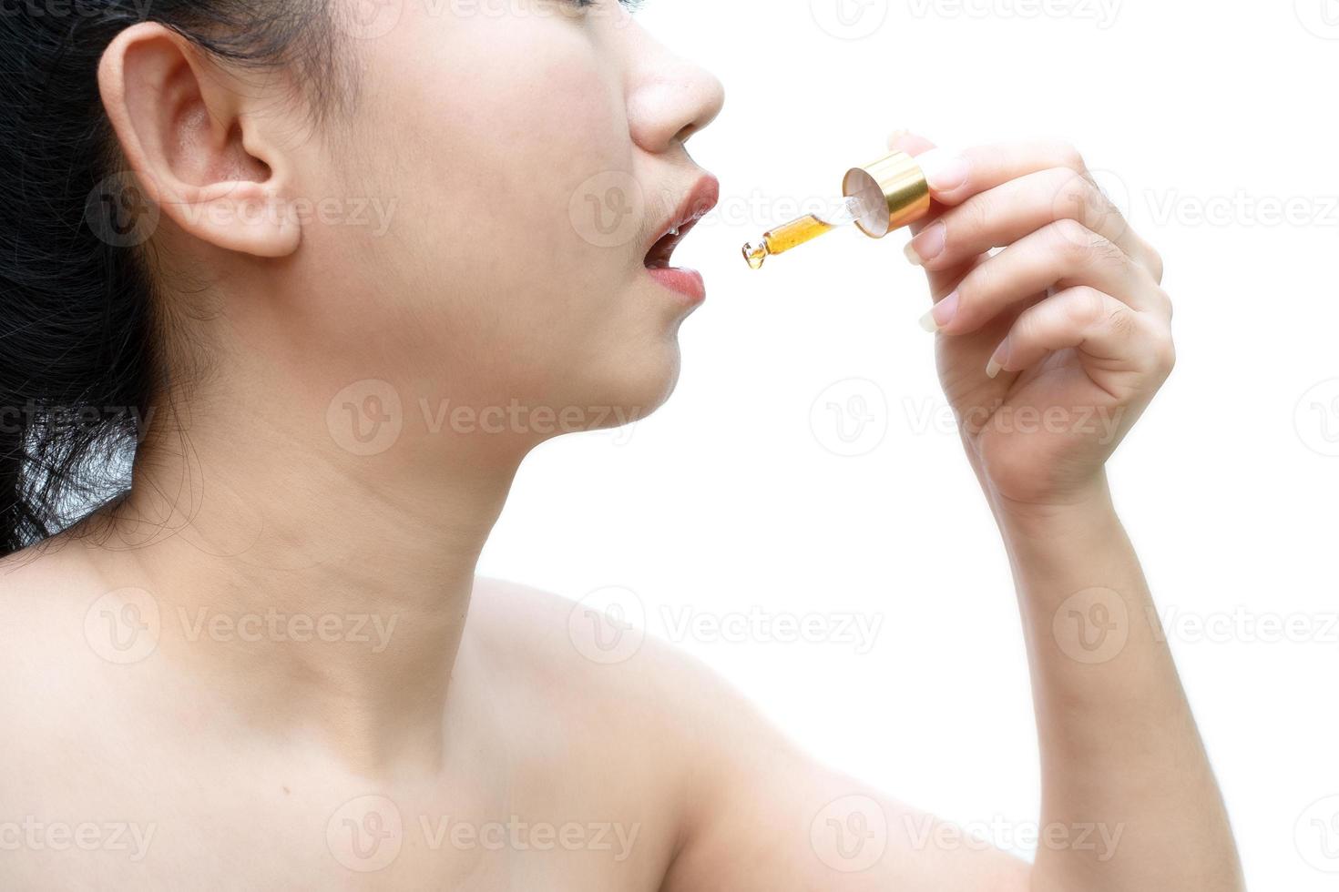 Femme tenant une huile de cannabis sublinguale compte-gouttes à fond blanc photo